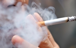 Smoking a cigarette with smoke around and a blurred background.