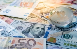 Global business and economy. World globe crystal glass on various international money banknotes. Currency exchange rate. Financial investment concept. Credit: Zephyr18/iStock