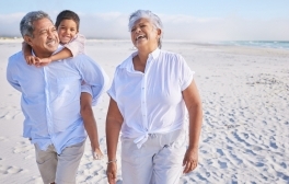 Two adult seniors walking on the beach with a child