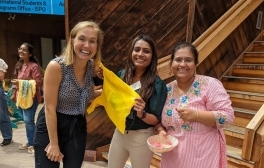 Three women smiling as they welcome guests to an international student program at UC San Diego.