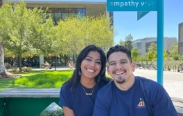 Photo of Paulina Cedillo and Carlos Garcia, second-year medical students sitting next to each other smiling in the UC San Diego School of Medicine courtyard area.