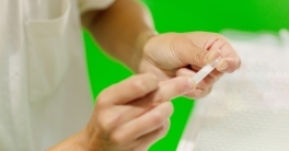 A close-up of two hands holding a vial of saliva