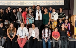 A large group of people from UC San Diego's Native American community as well as committee members who helped plan the annual Native American Heritage Month celebration pose on stage after the event.