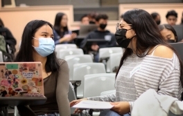A UC San Diego undergraduate student sits with a local high school student in a lecture hall to give personalized feedback on her personal insight questions as she prepares to submit a University of California application.