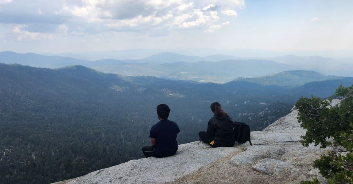 Students sit on a ledge and look out at the mountains