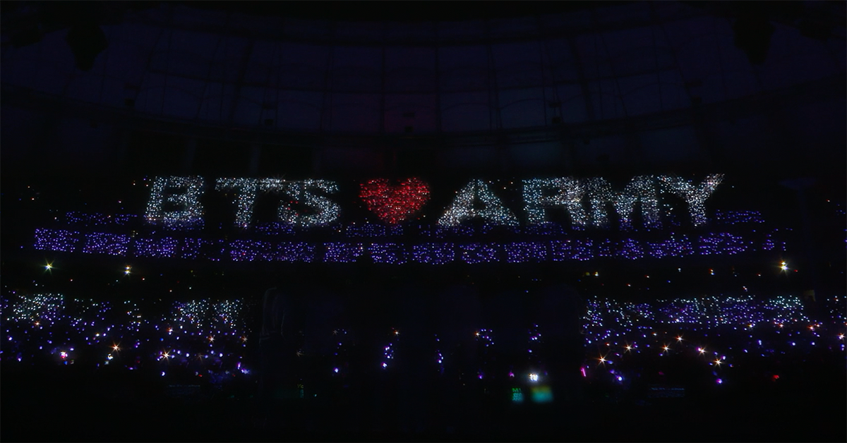 Nighttime BTS concert with stadium lit up to spell out 