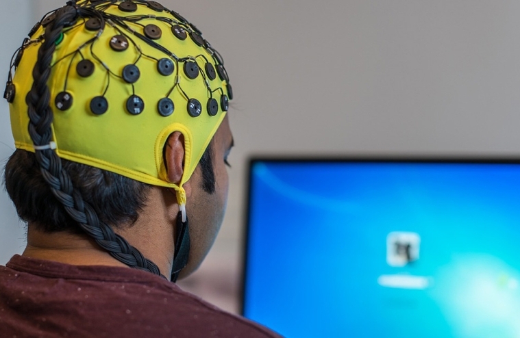Subject in EEG brain cap at computer