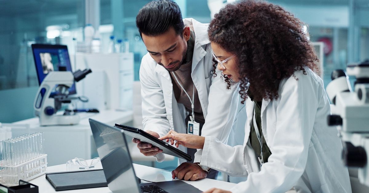 Two scientists/researchers in a laboratory discussing their work.