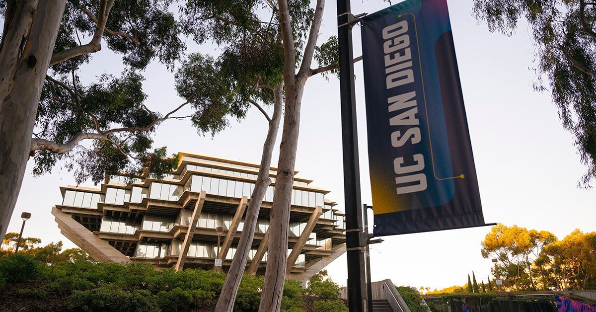 Geisel Library seen from behind UC San Diego banner on flag pole