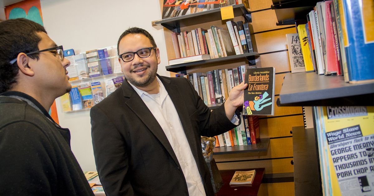 Gerardo Arellano holds up Borderlands book as he speaks with a student at the Raza Centro