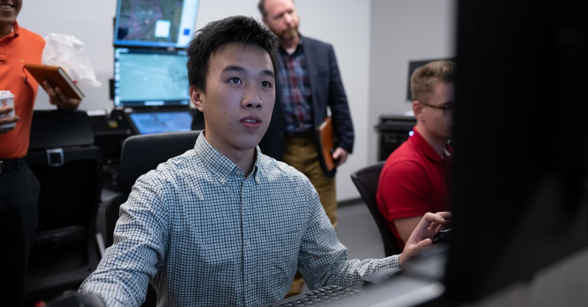 Student looks at big computer screen as others watch.