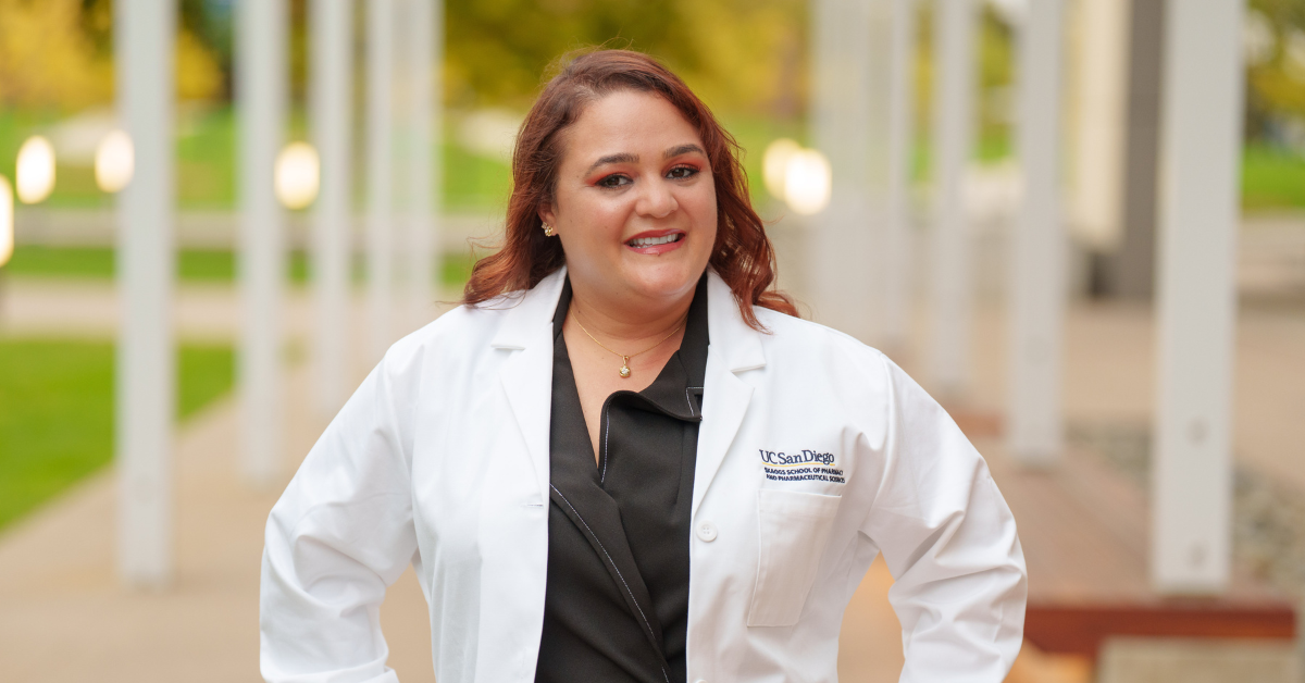 A smiling pharmacy student in a white coat
