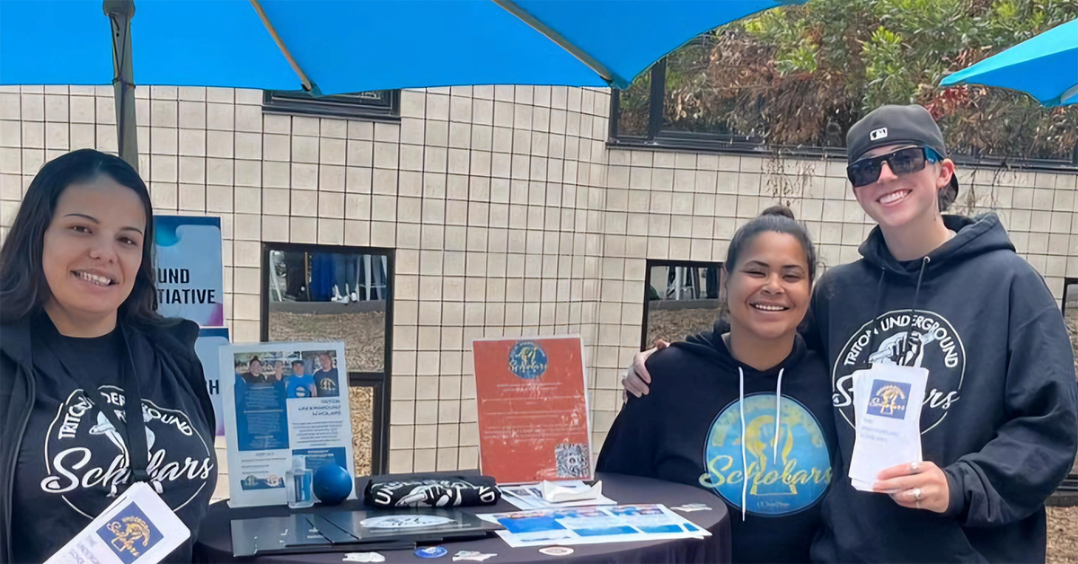 Students at table with promotional material about campus supports for formerly incarcerated and system-impacted students 