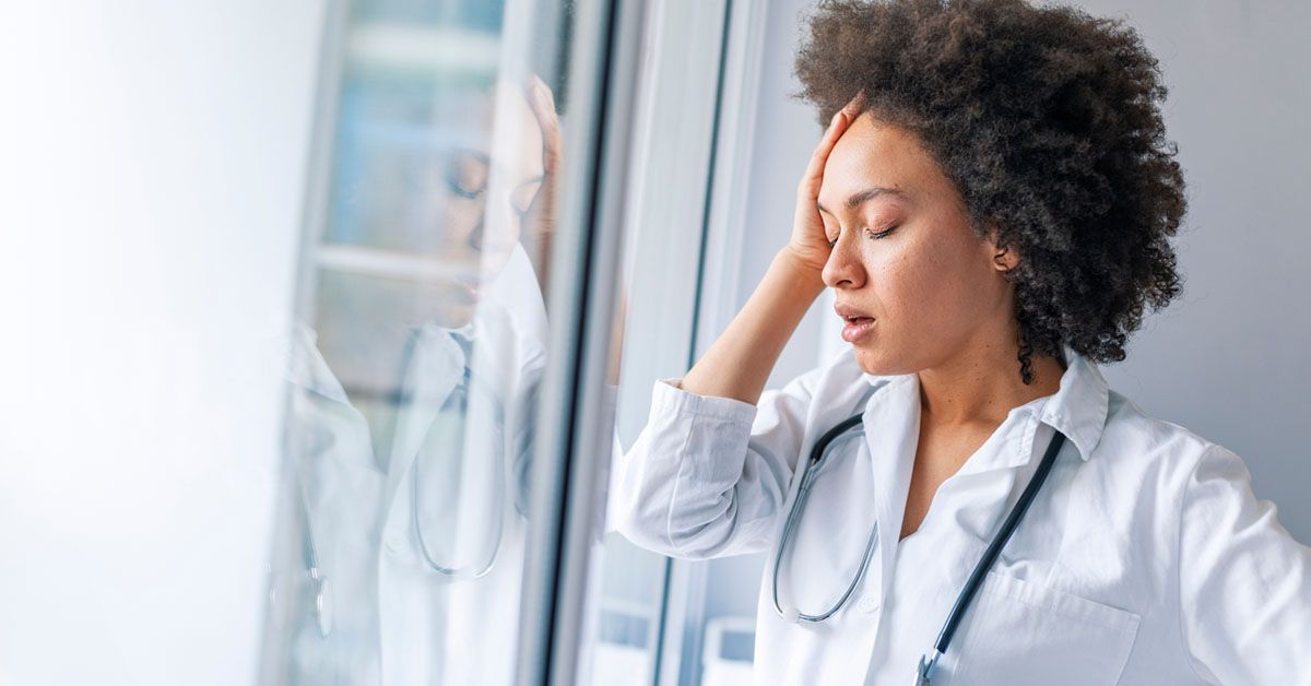 Nurse doctor with migraine overworked, overstressed isolated background hospital hall corridor. Tired female doctor near window in hospital. It's a stressful profession