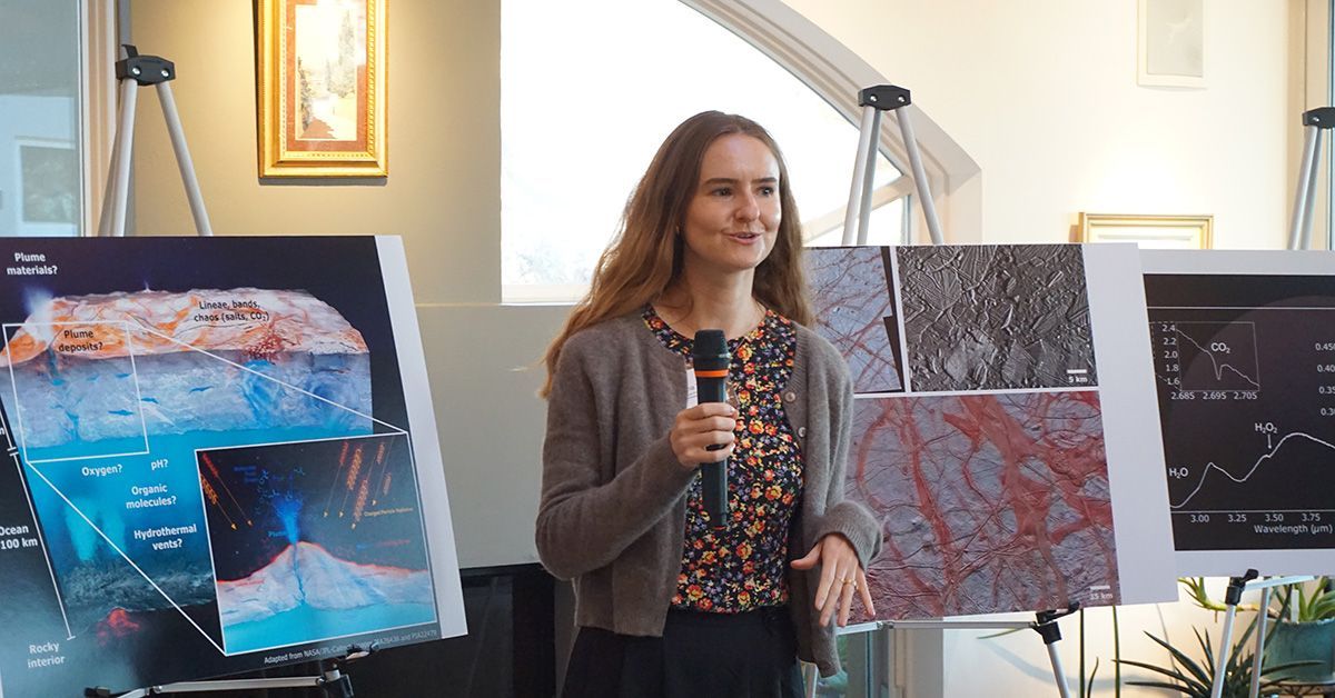 Samantha Trumbo talking with a microphone in front of posters