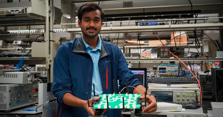 A Ph.D. student holds a prototype technology that offers more energy-efficient wireless connectivity. 