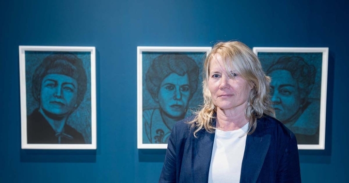 Artist Amy Adler in front of three portraits