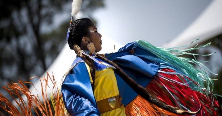 Two people dance in traditional Native American attire during a celebration on UC San Diego's campus.