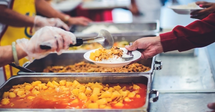 Volunteers serving hot meals to individuals at a community event. 