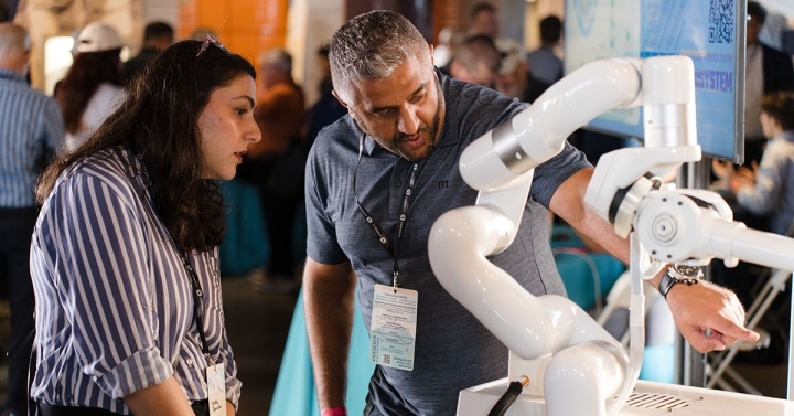 Demonstrator points at needle on AirSurgical's robot-guided ablation system as onlooker watches intently