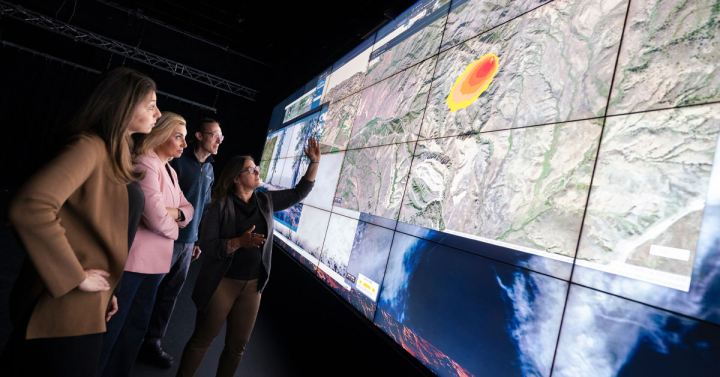 Four people examine wildfire visualizations on a large tiled-display.