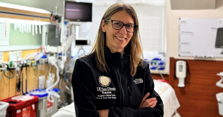 Laura Haines pictured in a hospital room with arms crossed wearing a branded UC San Diego Health jacket.