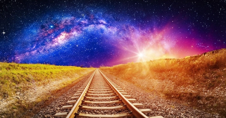 A train track heading into a cosmic looking night sky