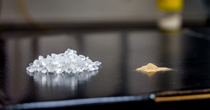 Pile of clear plastic pellets next to a pile of light brown powder.