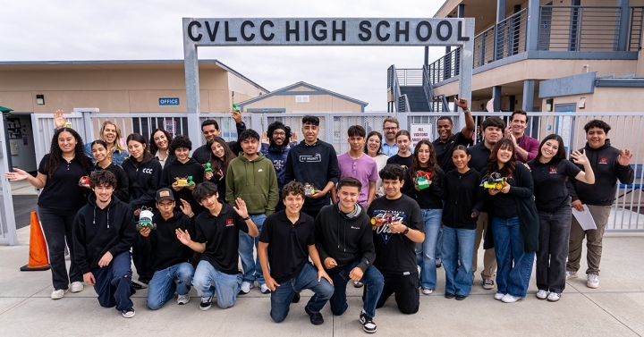 Students in the ECE5: Making, Breaking and Hacking Stuff course stand outside their Chula Vista Learning Community Charter School sign.