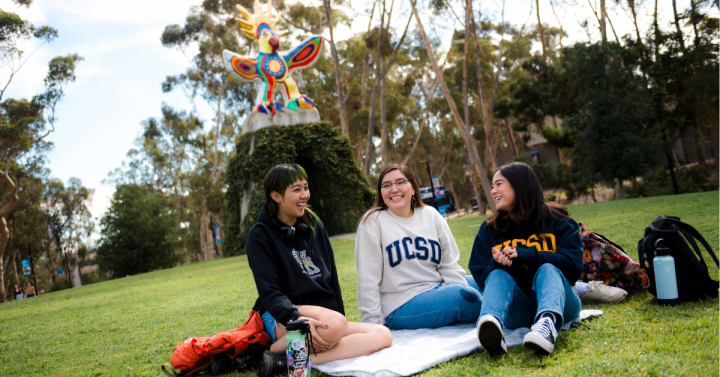 Four students gather on Sun God Lawn. 
