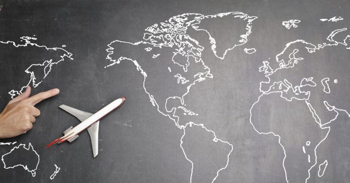 Airplane over world map on blackboard
