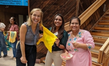 Three women smiling as they welcome guests to an international student program at UC San Diego.