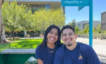 Photo of Paulina Cedillo and Carlos Garcia, second-year medical students sitting next to each other smiling in the UC San Diego School of Medicine courtyard area. 
