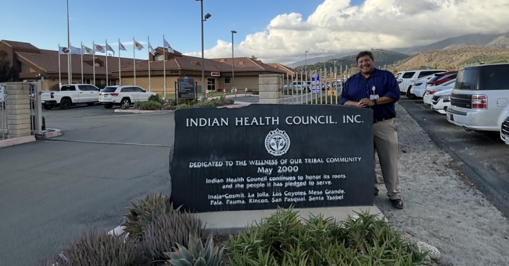 Dr. Dan Calac, chief medical officer at the Indian Health Center standing next to the IHC sign at the entrance to the facility. 