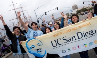 A group of UC San Diego students hold a large banner depicting Martin Luther King Jr. as they march in the parade downtown. 
