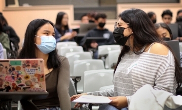 A UC San Diego undergraduate student sits with a local high school student in a lecture hall to give personalized feedback on her personal insight questions as she prepares to submit a University of California application.