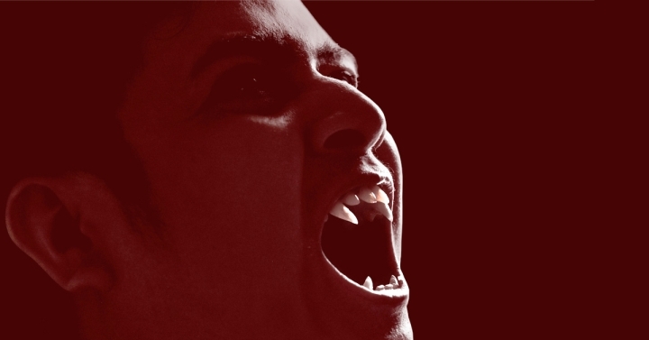 Close-up of a man wearing fangs to mimic a vampire.