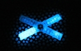 X-shaped object glows blue in the dark.