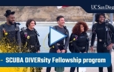 Video: A group of people dressed in scuba gear stand on a pier.