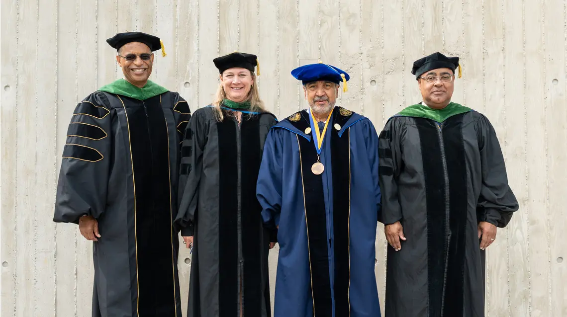 John Carethers, Barbara Jung, Predeep Khosla and Byron Scott all smiling wearing graduation regalia