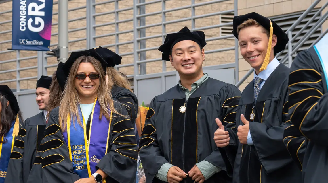 Brianna Irons, smiling facing camera with two male classmates.