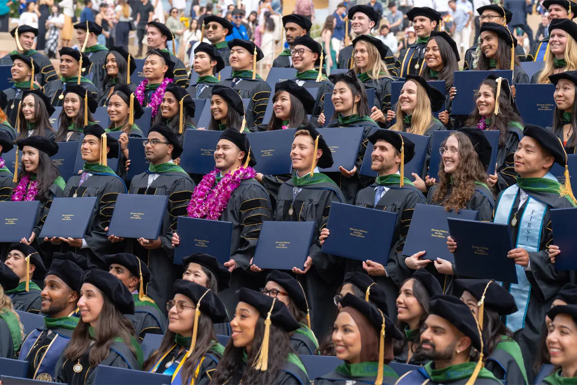 Group photo of School of Medicine graduates in regalia holding diploma covers