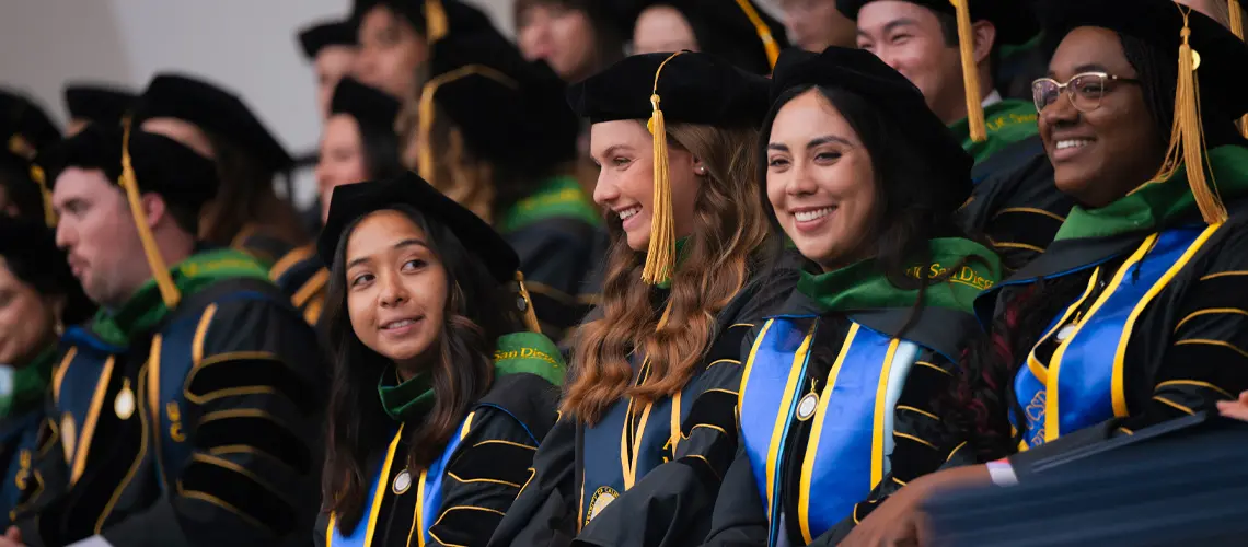 Group of medical students on stage wearing commencement regalia during the ceremony