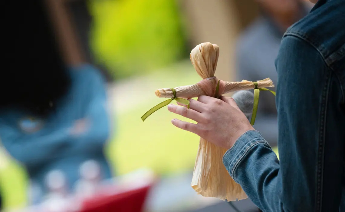 close up of female hand holding a cornhusk doll, the background is blurred