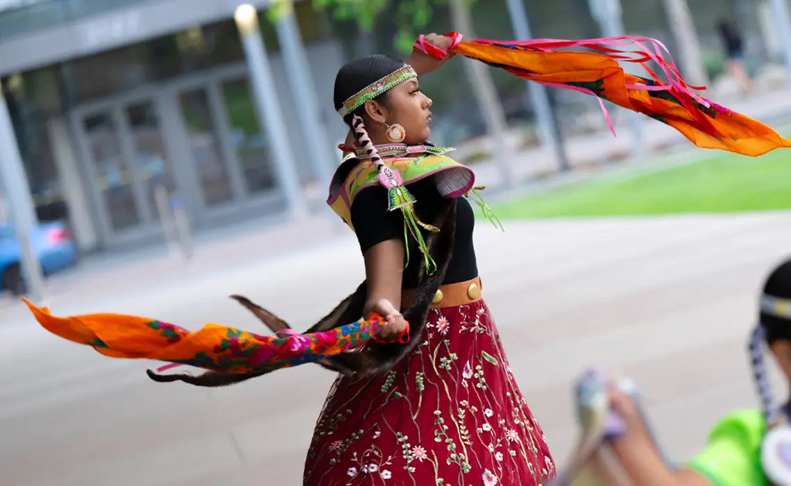 Female dancer performing with red and orange colored scarves