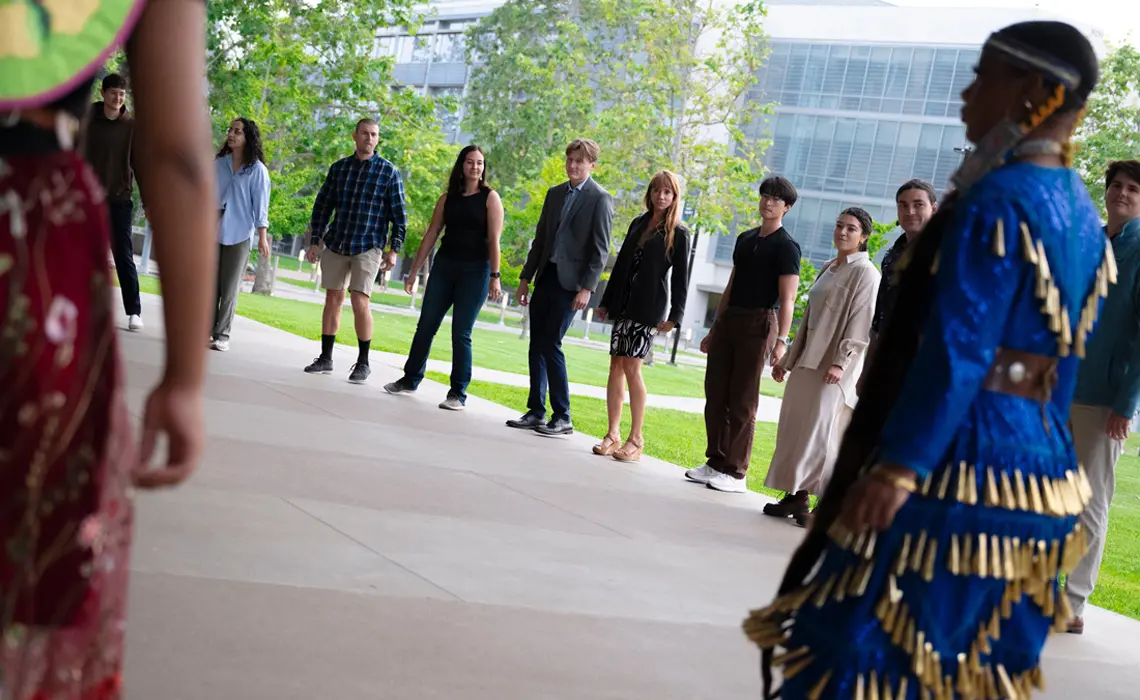 Powwow dancers in a circle with ceremony attendees for a Round Dance