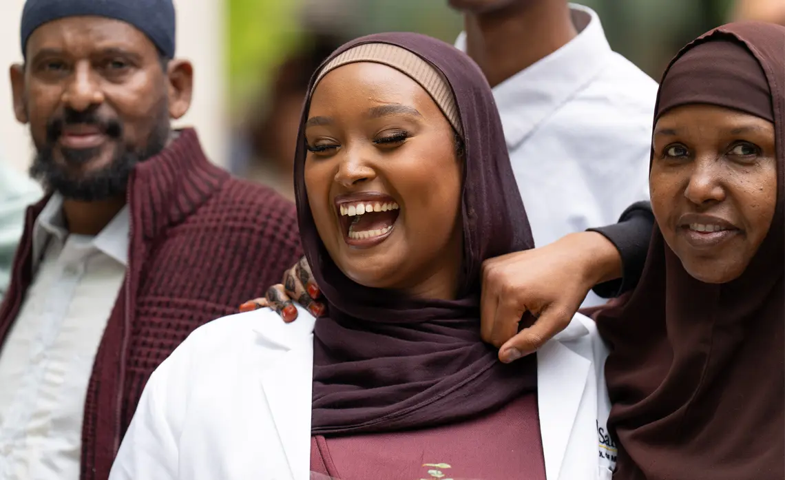 Female student of Somalian decent smiling broadly surrounded by family members