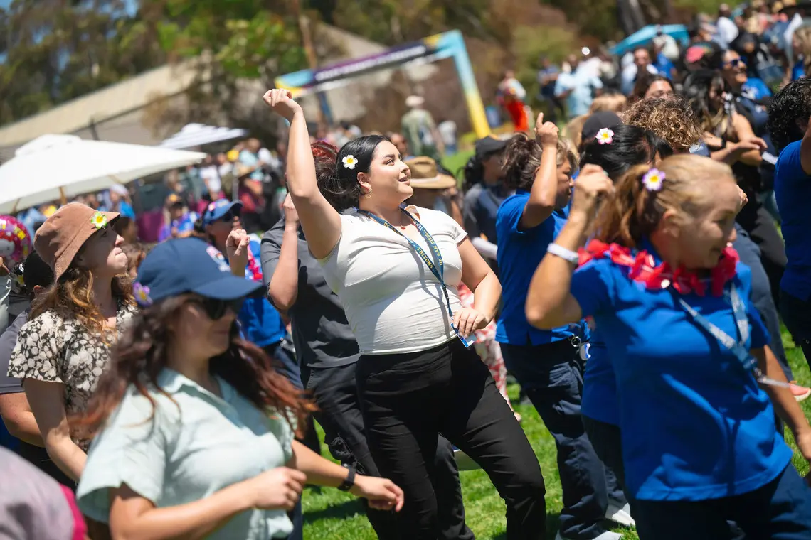 Staff members doing a line dance on Sun God Lawn