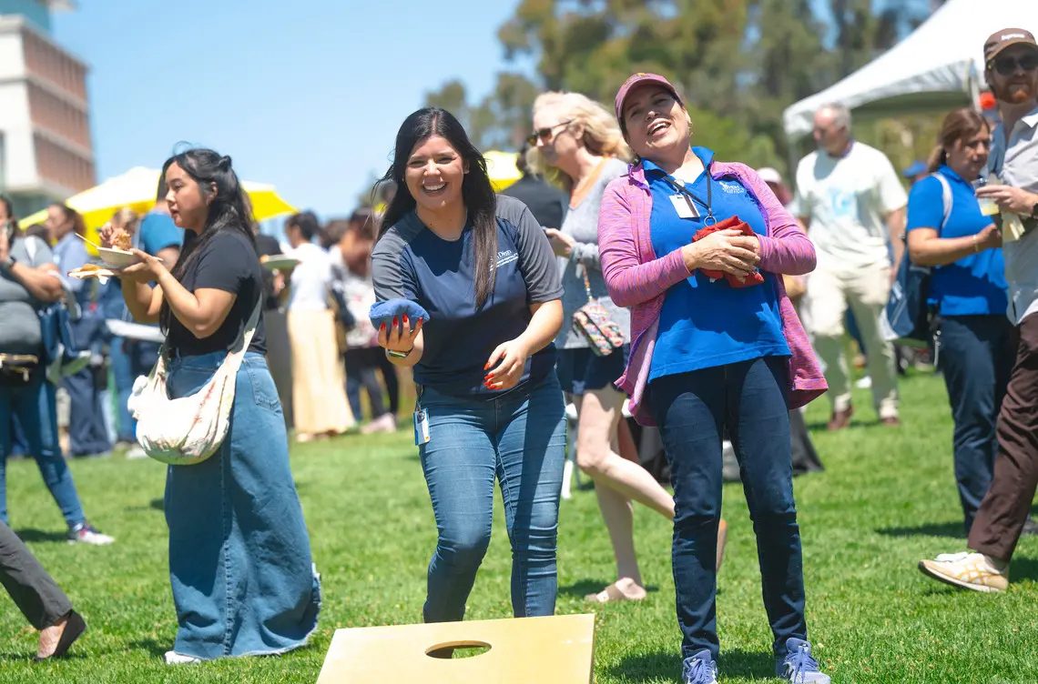 Staff members play a game of corn hole.