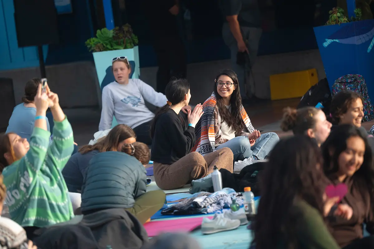 Students sit on yoga mats talking to each other